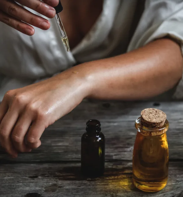 Therapist applying massage oil to a client's arm on the treatment table